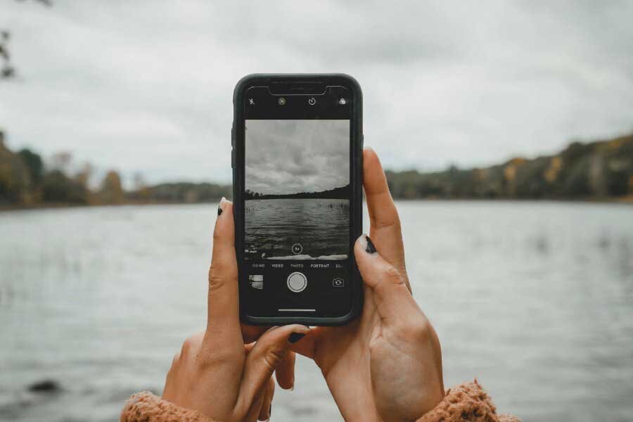 Mobile phone held in front of a lake.