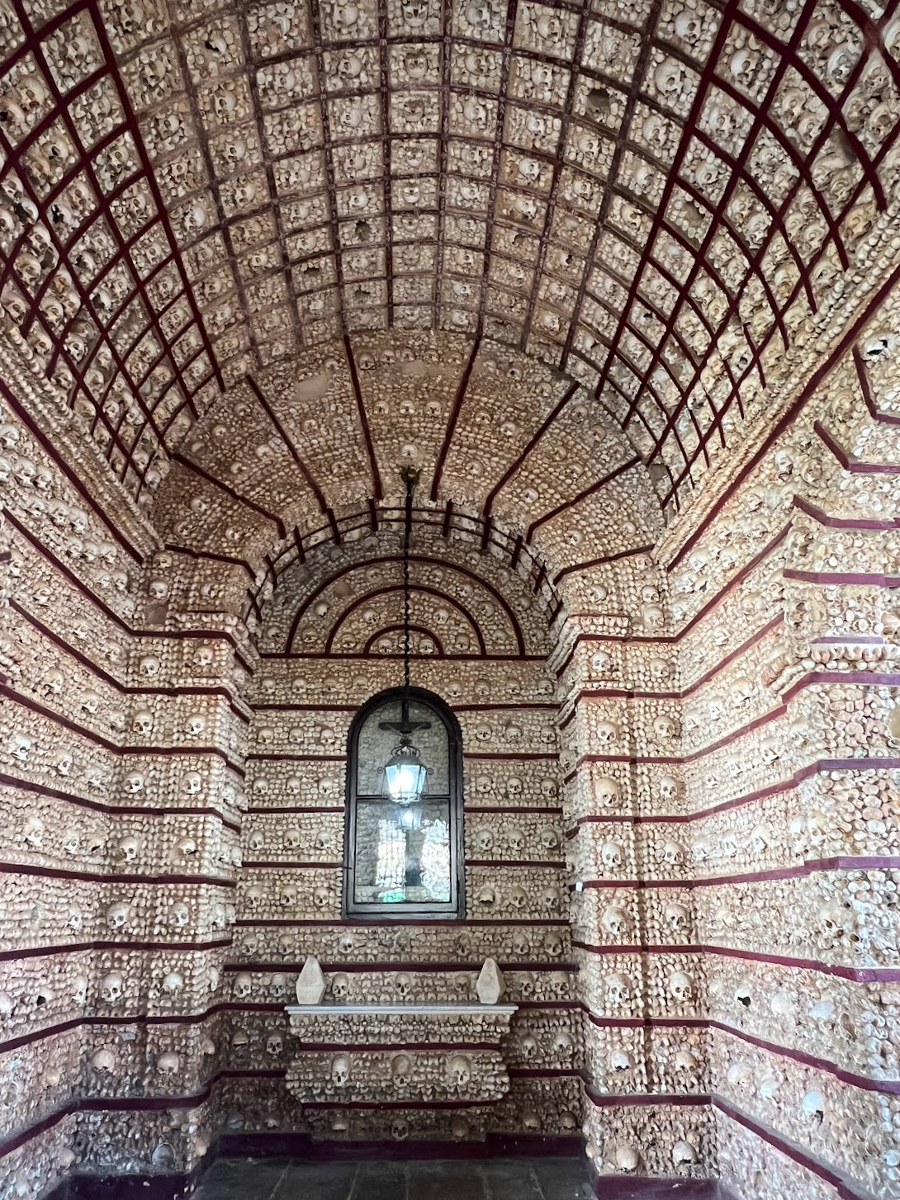 The inside of a small chapel - the walls and ceiling of which have been segmented into 1000 boxes. Each box is filled with the skull and bones of a monk.