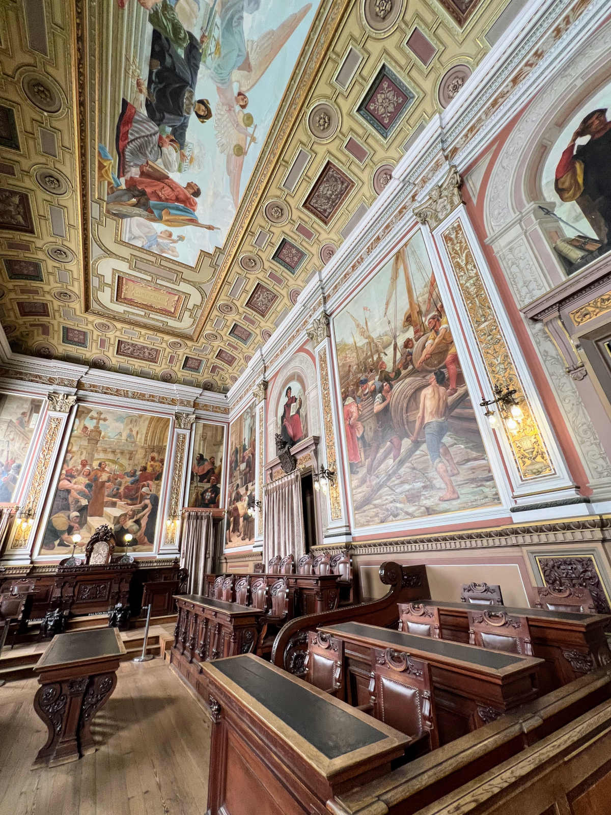 Old fashioned jury room with intricately painted scenes adorning the ceiling and walls.
