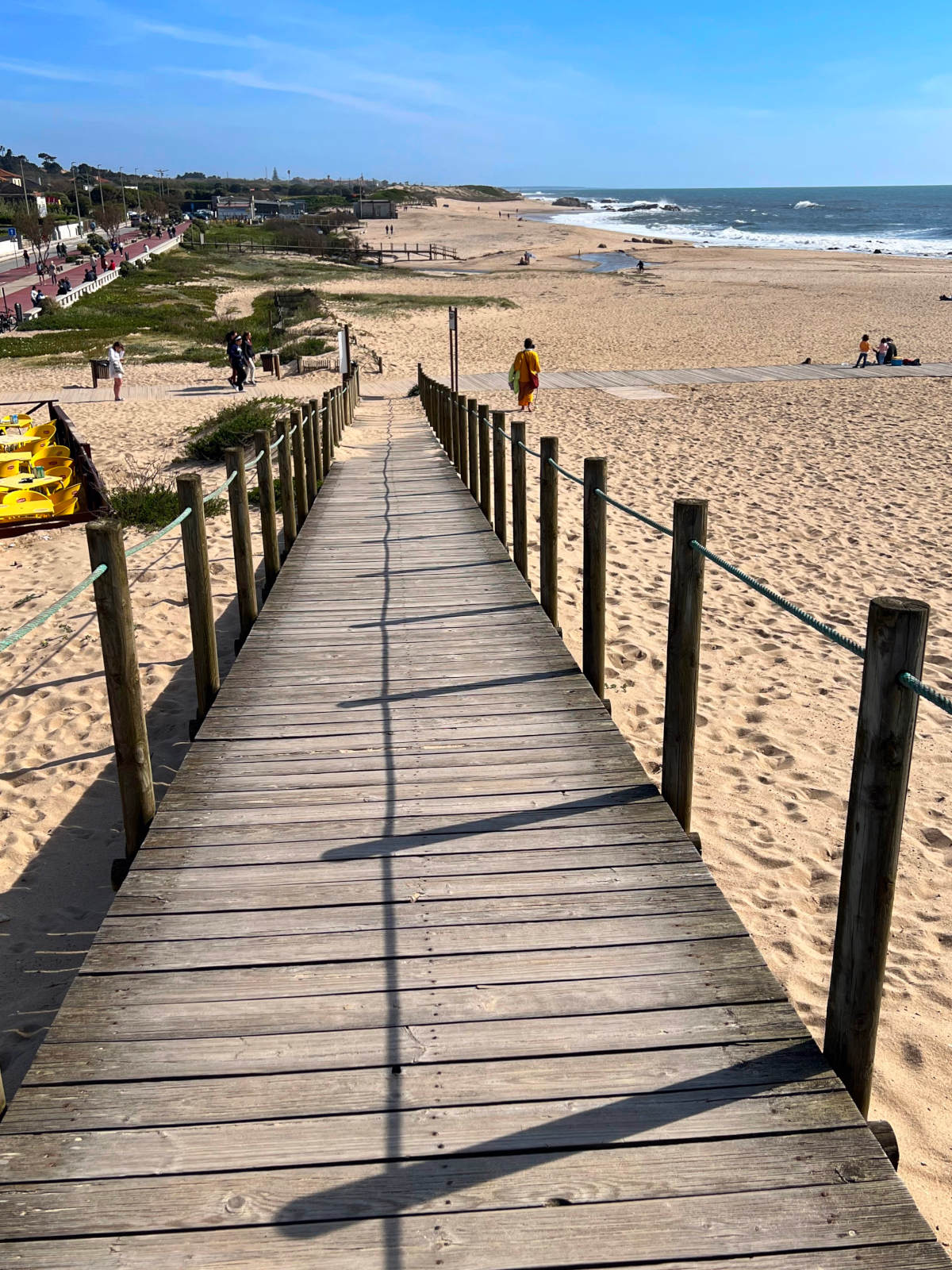 A pedestrian boardwalk running behind an expansive golden sand beach.